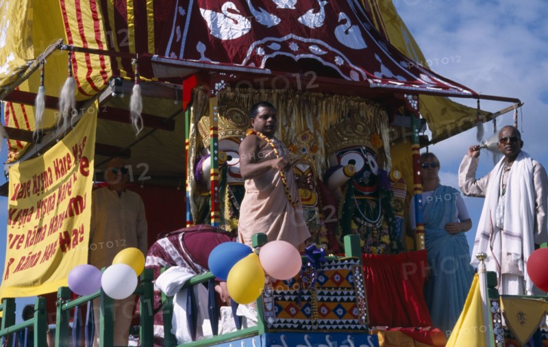 ENGLAND, East Sussex, Brighton, Hare Krishna taking part in a parade on Brighton seafront  with a colourful painted carriage