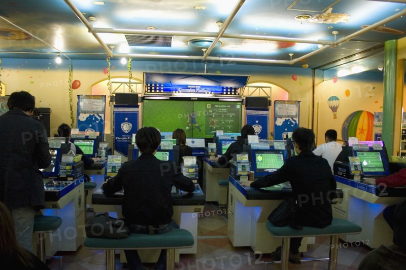 JAPAN, Honshu, Tokyo, Shinjuku.  Young Japanese seated in front of computer screens soccer video game.