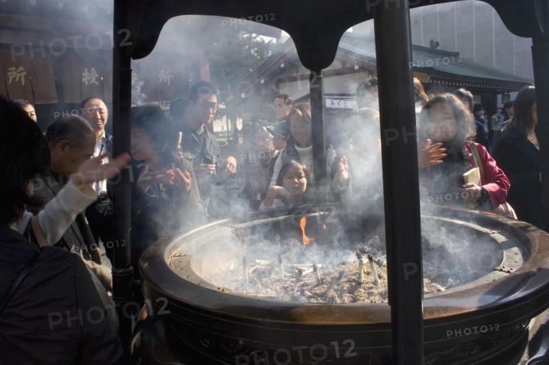 JAPAN, Honshu, Tokyo, Asakusa Kannon or Senso-ji Temple.  Japanese people wafting smoke from incense burner or joukoro over themselves in belief that it will keep them in good health.
