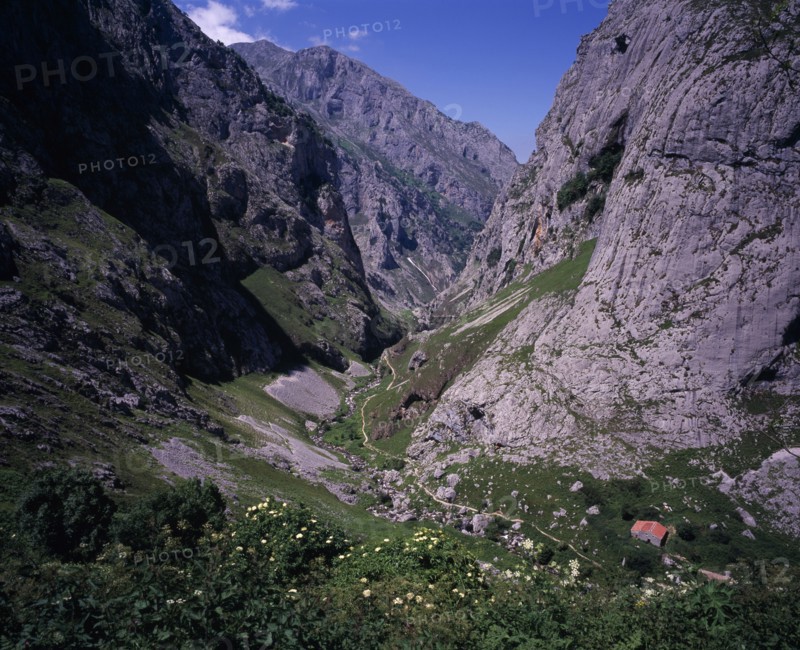 SPAIN, Asturias, Picos de Europa, "View north down Arroyo del Tejo Valley from Bulnes El Castillo with steep sided, eroded limestone cliffs and narrow, winding mountain path."