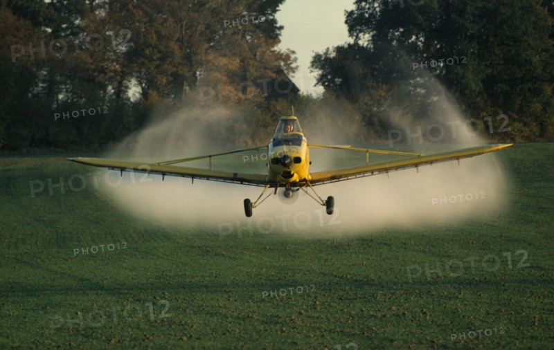 ENGLAND, West Sussex, Slinfold, Yellow plane crop spraying