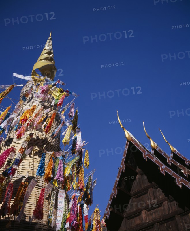 THAILAND, North, Chiang Mai, Wat Phran Tao.  Detail of pointed roof top of rare teak temple beside woven tower decorated by children with coloured paper flags and offerings.