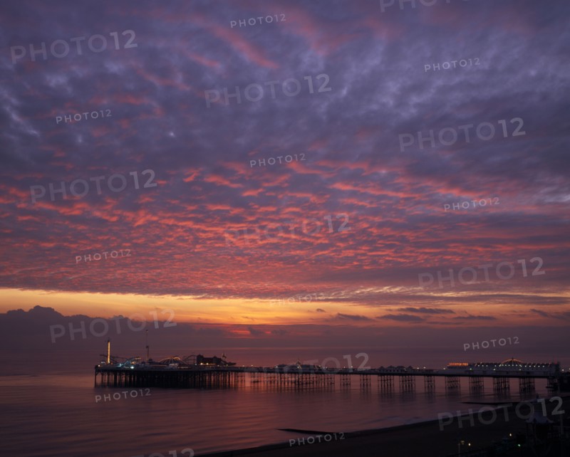 ENGLAND, East Sussex, Brighton, Early Autumn sunset from Marine Parade with Brighton Pier and street lights illuminated.