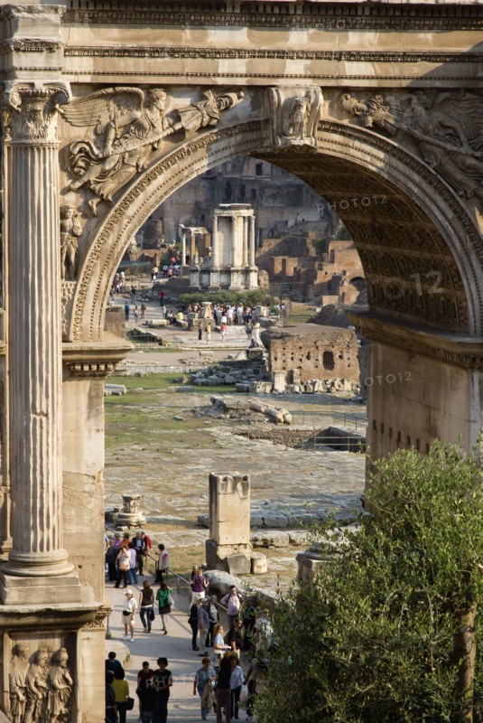 ITALY, Lazio, Rome, Tourists walking in the Forum with the Temple of The Vestals seen through the Arch of Septimius Severus