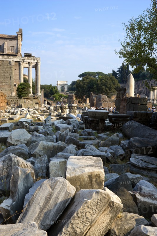 ITALY, Lazio, Rome, Fallen remains of buildings in the Forum with the Temple of Antoninus and Faustina on the left and the Arch of Titus in the distance