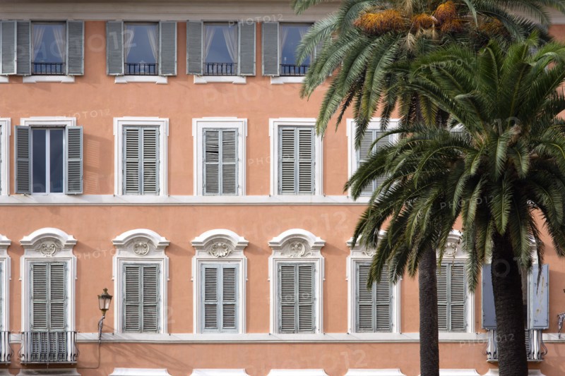 ITALY, Lazio, Rome, Palm trees in front of a pink building with pale blue shuttered windows in Piazza di Spagna