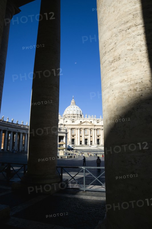 ITALY, Lazio, Rome, Vatican City The Basilica of St Peter and the square or Piazza San Pietro with tourists seen through the columns of Bernini