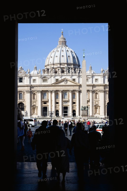 ITALY, Lazio, Rome, Vatican City Silhouette of tourists passing through an arch leading to the Piazza San Pietro or St Peter's Sqaure with the Basilica of St Peter beyond