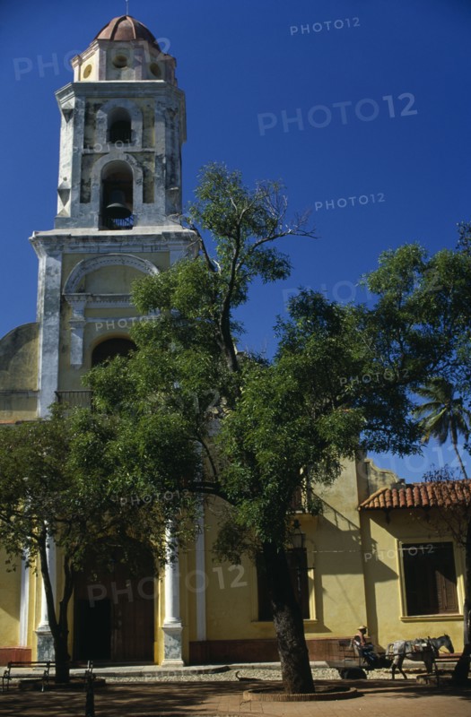 CUBA, Trinidad de Cuba, "Exterior of the former church now a museum of the revolutionary struggle. National Museum of the Struggle Against the Bandits, previously a church and convent of San Francisco. Passing horse drawn cart, tree in foreground."