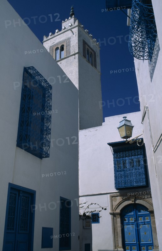 TUNISIA, Sidi Bou Said, "Part view of white painted mosque with decorative, blue painted balconies, window shutters and doorway."