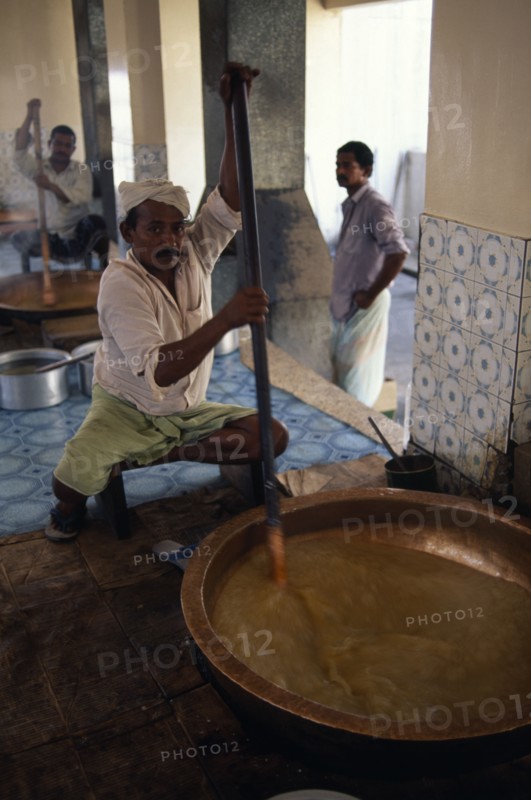 OMAN, Muscat, "Men stirring large, shallow dish of halva."