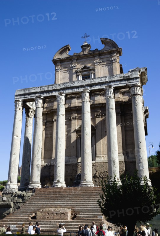 ITALY, Lazio, Rome, Tourists in the Forum walking past the portico of the Temple of Antoninus and Faustina incorporated into the church of Sant Lorenzo in Miranda