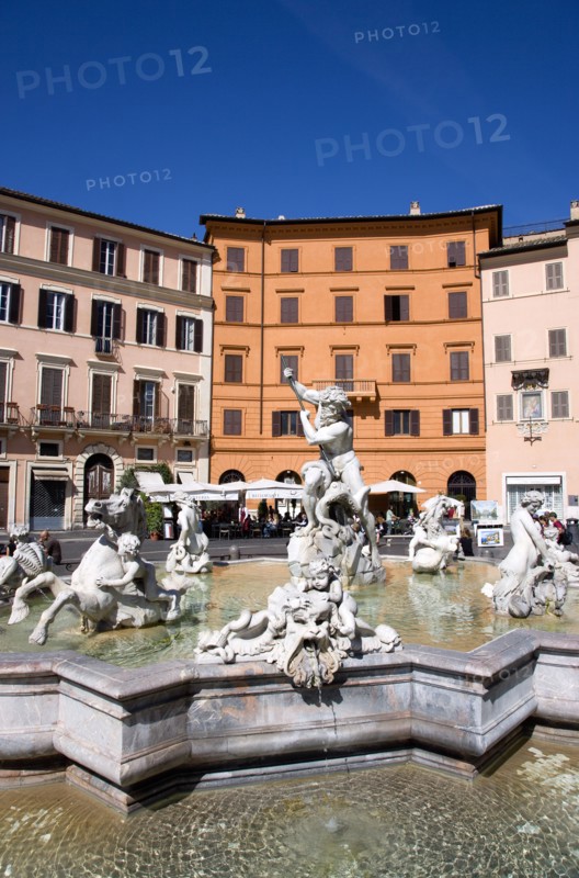 ITALY, Lazio, Rome, The Fountain of Neptune or Fontana del Nettuno in the Piazza Navona with tourists walking past restaurants beyond