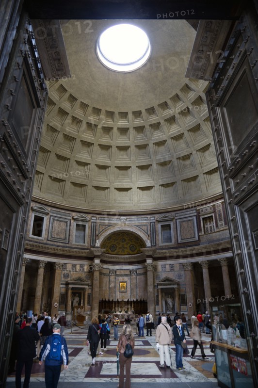 ITALY, Lazio, Rome, The interior of the Pantheon showing the oculus central opening and the coffering construction of the dome with tourists walking on the patterned marble flooring