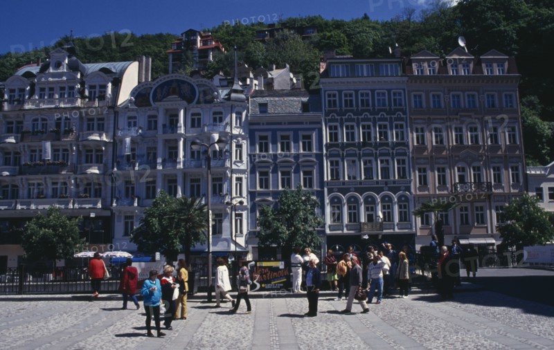 CZECH REPUBLIC, Western Bohemia, Karlovy Vary, "Square in spa city with crowds of visitors overlooked by tall, narrow buildings painted in pastel colours. "