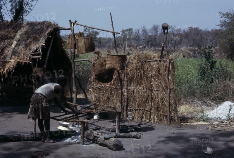 MALAWI, Tribal People, Yau Tribe, Yau village with man cooking over an open fire