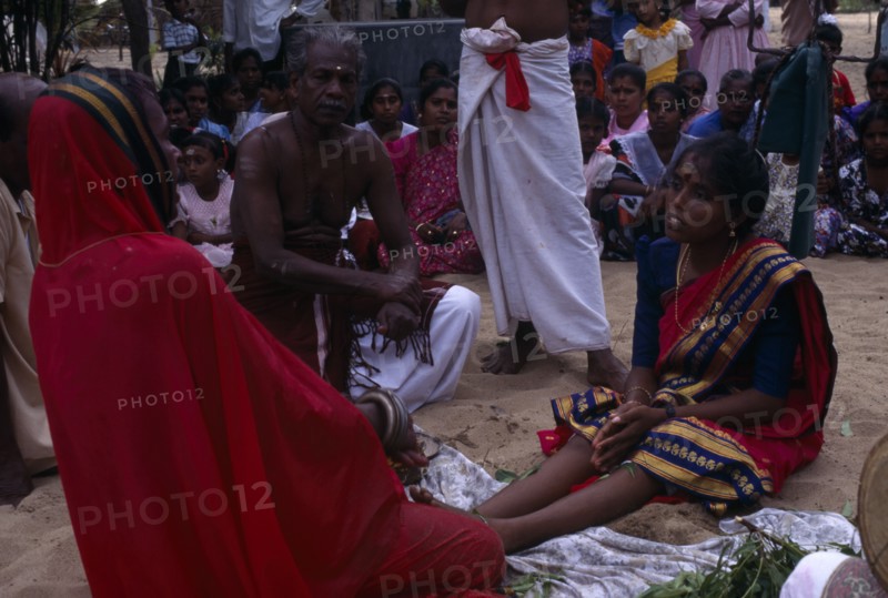 SRI LANKA, Religion, Hinduism, Punnaccolai Festival. Hindu Tamil Priest wearing a red robe performing a curing / healing Puja on a woman