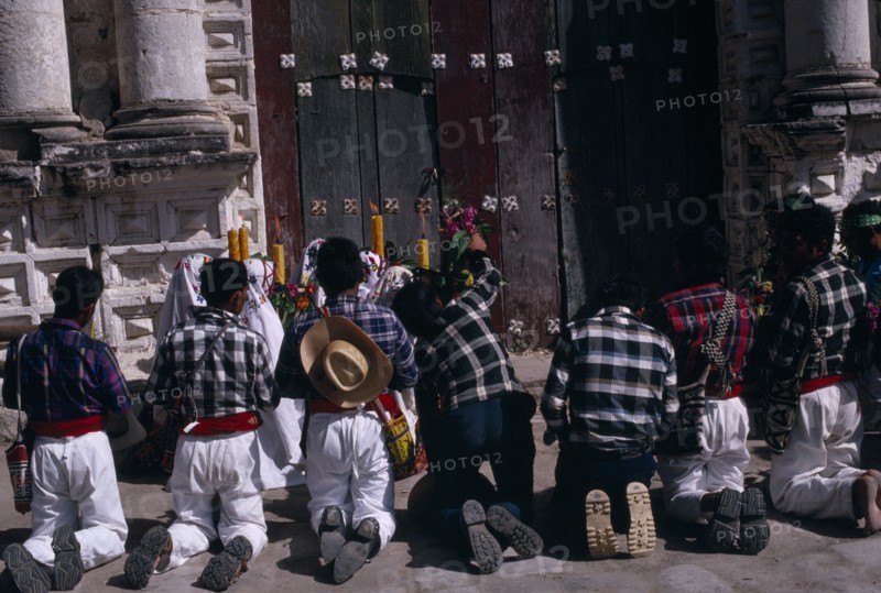 GUATEMALA, El Quiche, San Andres de Sajcabaja, Quiche Indian men kneeling in prayer outside the 16th century church during San Andres Festival on December 8th