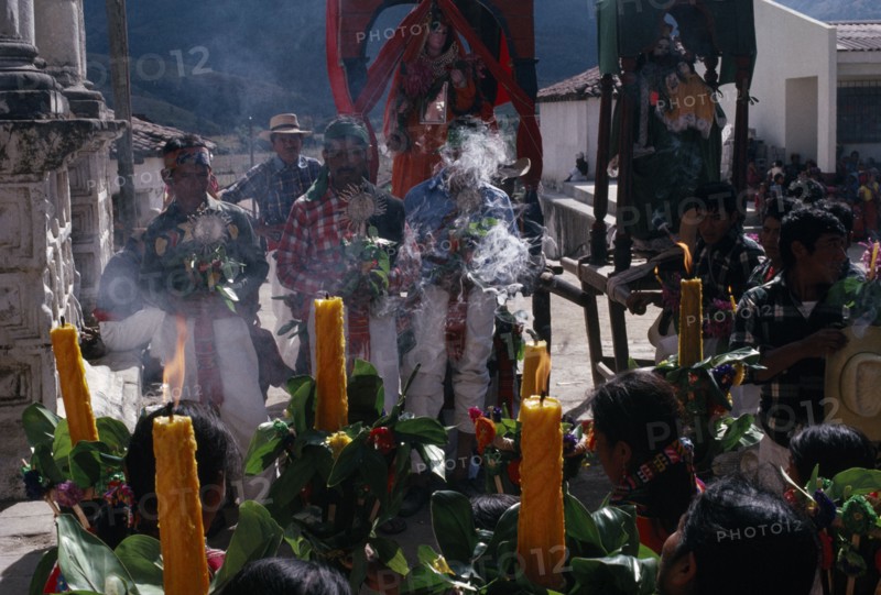 GUATEMALA, El Quiche, San Andres de Sajcabaja, Quiche Indian women holding candles facing Confradia brotherhood and Saints during San Andres Festival on December 8th