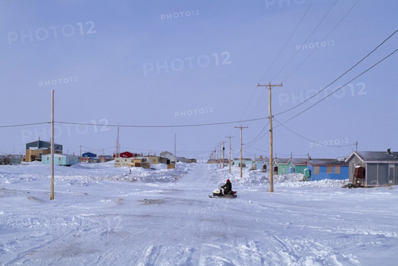 CANADA, Quebec, Hudson Bay, The Great Whale Settlement. Cree indigenous community. Housing and roads in heavy snow cover with a skidoo travelling past.