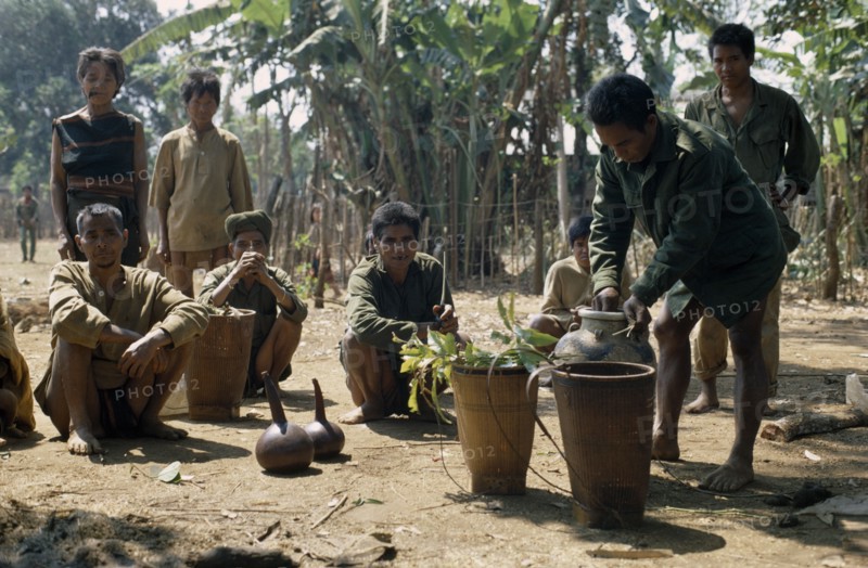 VIETNAM, Central Highlands, Pleimurong village, "Vietnam War. Montagnard village soldiers filling finely woven bamboo rice-carrier baskets, prpearing to make rice wine."