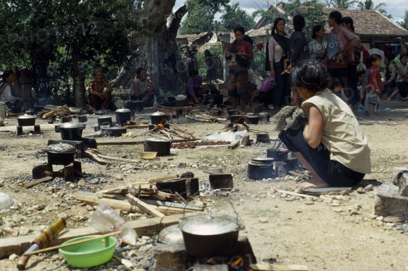 VIETNAM, Central highlands, Kontum, Vietnam War. Montagnard refugee camp in Siege of Kontum. Woman tending open fireplace  with cooking pots of rice.