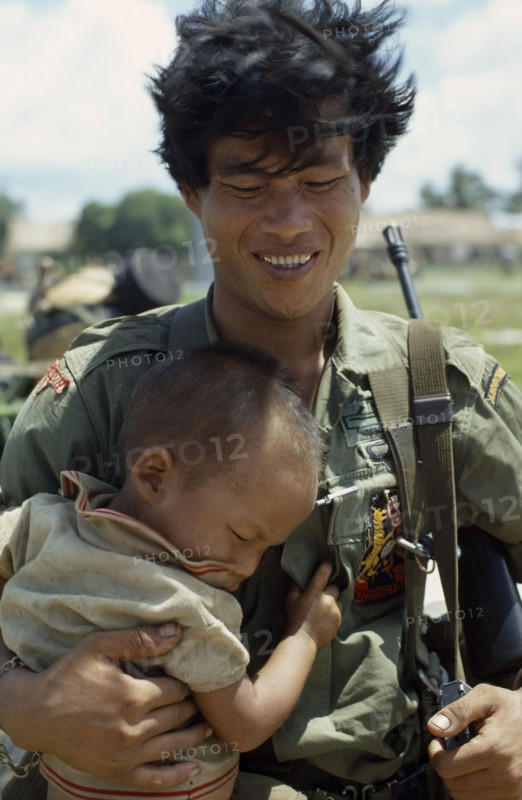 VIETNAM, Central Highlands, Kontum, Vietnam War. Siege of Kontum. Montagnard soldier carrying his baby son