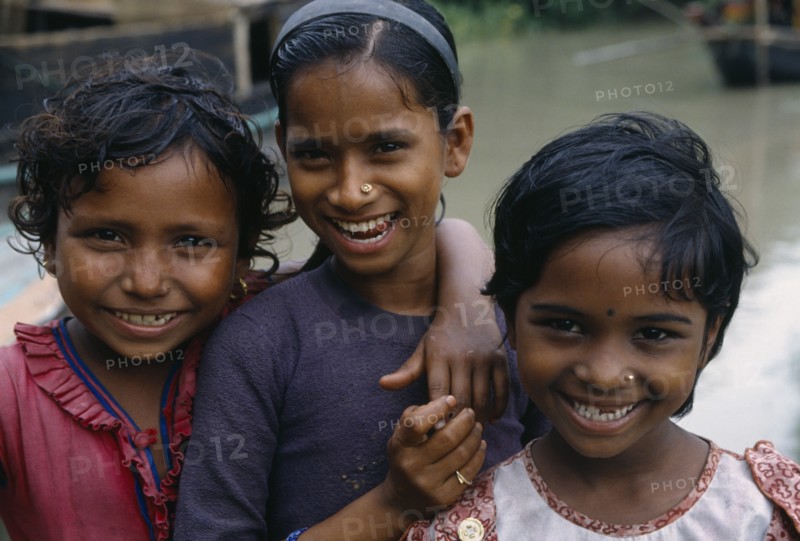 BANGLADESH, Khulna, Char Kukuri Mukuri, Head and shoulders group portrait of three smiling young girls.