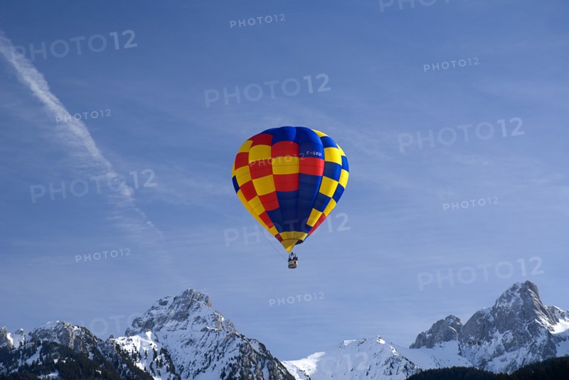 SWITZERLAND, Canton de Vaud, Chateau d'Oex, One Hot Air Balloon in flight above jagged snow covered peaks.