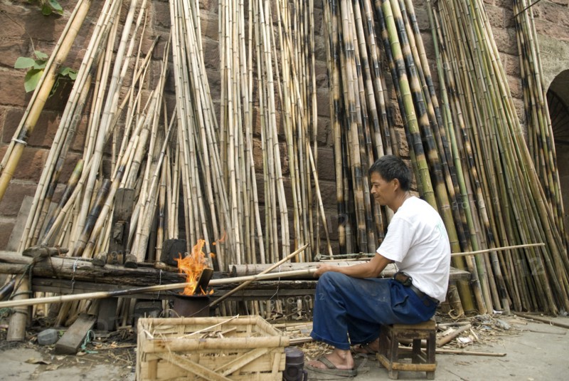 CHINA, Sichuan Province, Chongqing, Man strengthening bamboo joints with fire