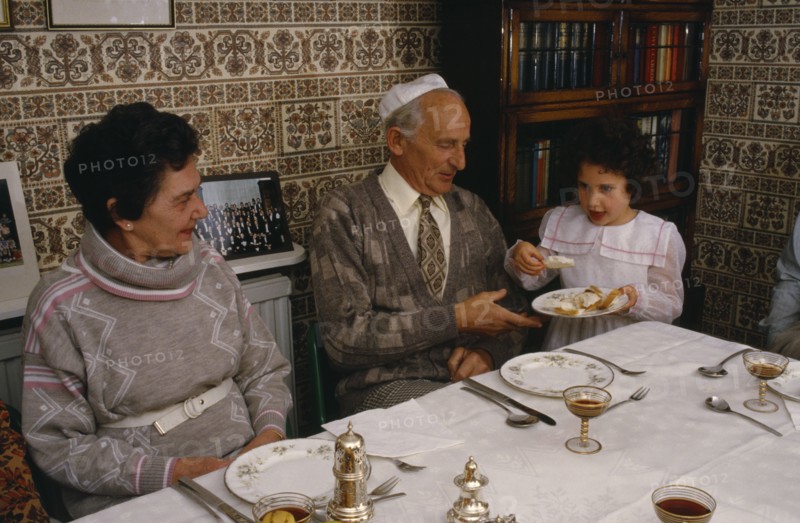 ENGLAND, Religion, Judaism, "Jewish New Year meal, young girl passing the chala or bread to family members."