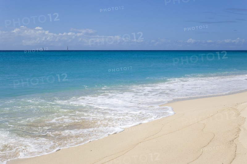 WEST INDIES, St Vincent And The Grenadines, Canouan, South Glossy Beach in Glossy Bay with waves breaking on the shoreline of the turqoise sea and yachts on the horizon