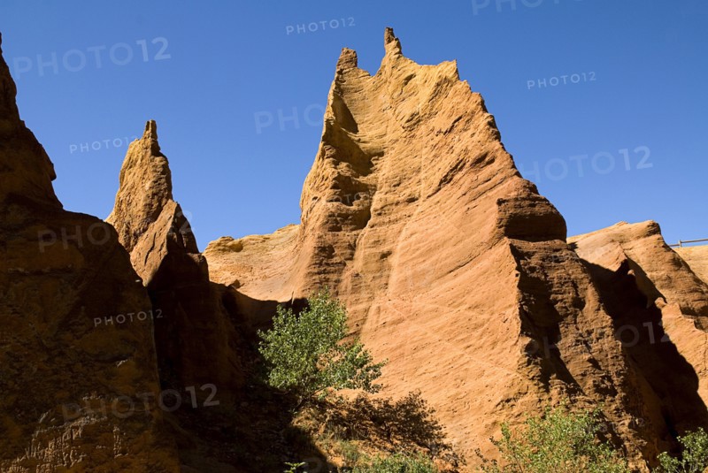 FRANCE, Provence Cote d’Azur, Vaucluse, Colorado Provencal.  Cheminee de Fee or Fairy Chimneys.  Looking up eroded ochre cliff face topped by jagged peaks from park trail below.