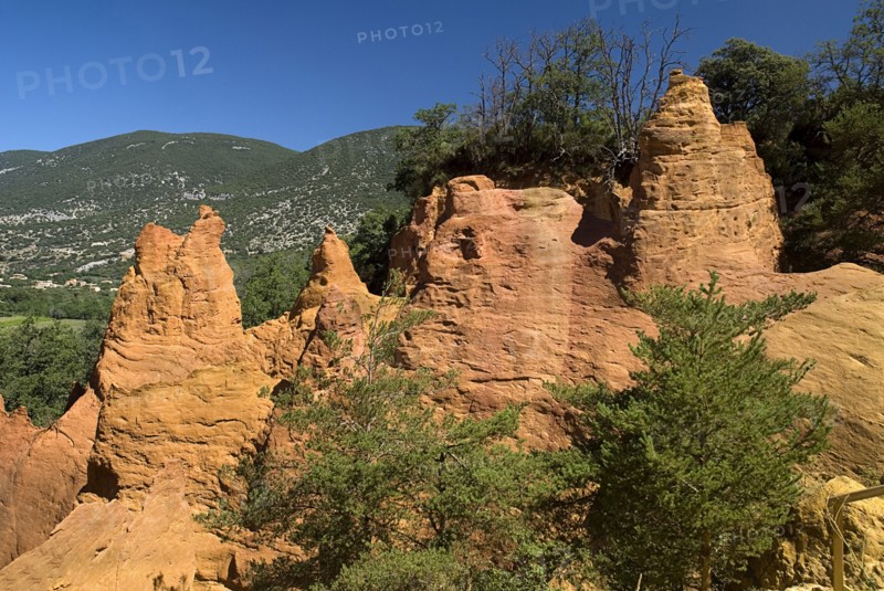 FRANCE, Provence Cote d’Azur, Colorado Provencal.  Cheminee de Fee or Fairy Chimneys.  Eroded ochre rock forms and surrounding landscape from viewpoint.