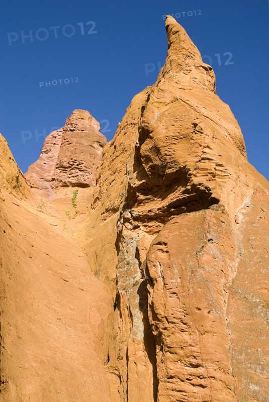 FRANCE, Provence Cote d’Azur, Vaucluse, "Colorado Provencal.  Cheminee de Fee or Fairy Chimneys.  View of eroded, ochre rock forms against cloudless blue sky from the park trail."