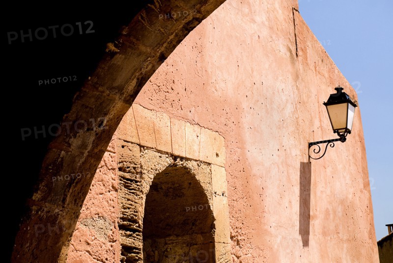FRANCE, Provence Cote d’Azur, Vaucluse, Roussillon.  Architectural detail of archway framing street light on red exterior wall of town building.