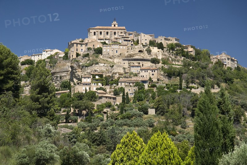 FRANCE, Provence Cote d’Azur, Vaucluse, Gordes.  View of hilltop village from the road below with church at summit.