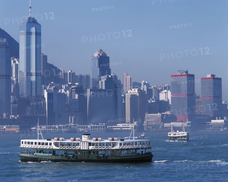CHINA, Hong Kong, Victoria Harbour, Star Ferries crossing Victoria Harbour with high rise buildings on city skyline beyond.