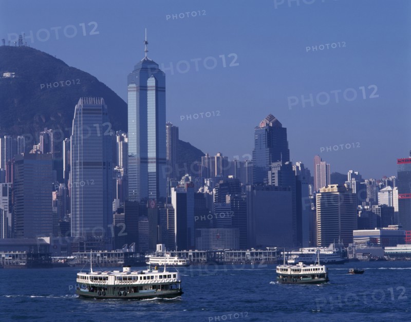 CHINA, Hong Kong, Victoria Harbour, Star Ferries crossing Victoria Harbour with high rise buildings on city skyline beyond.