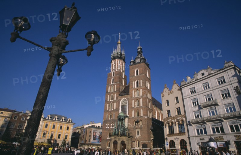 POLAND, Krakow, Mariacki Basilica or Church of St Mary.  Gothic  red brick exterior built in the fourteenth century overlooking the main market square with street lamp in foreground.