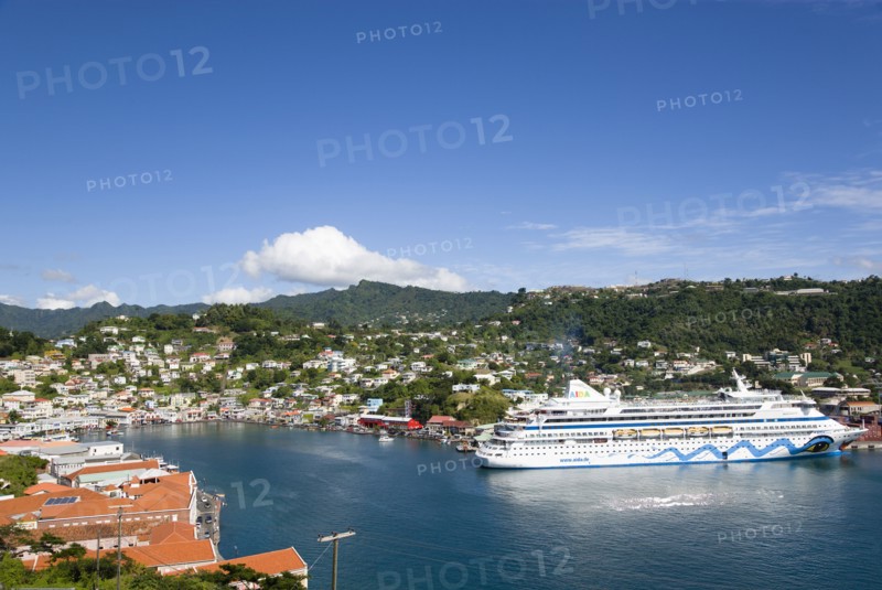 WEST INDIES, Grenada, St George, The Carenage harbour of the capital city of St George's surrounded by hills lined with houses and other buildings and the cruise ship Aida Aura moored at the docks