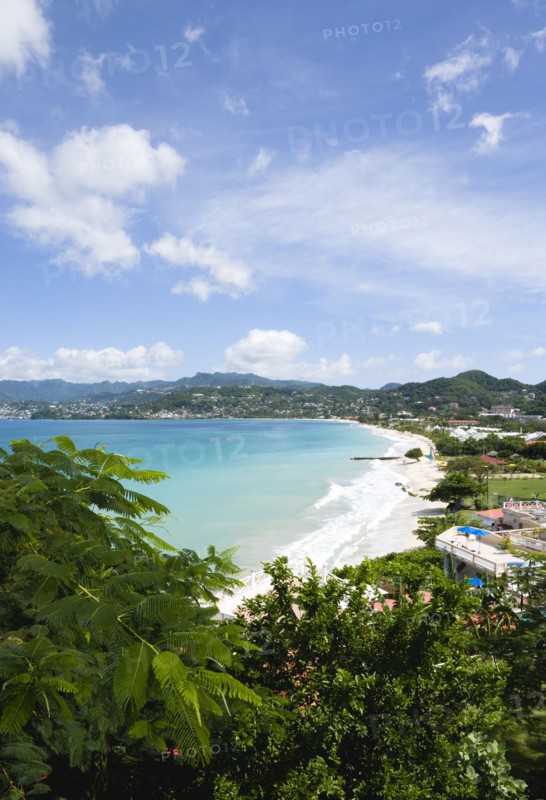 WEST INDIES, Grenada, St George, Gentle waves of the aquamarine sea breaking on the two mile stretch of the white sand Grand Anse Beach with the capital city of St George's in the distance