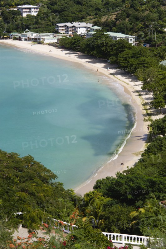 WEST INDIES, Grenada, St George, The aquamarine sea and tree lined white sand of BBC Beach in Morne Rouge Bay with tourists walking on the beach