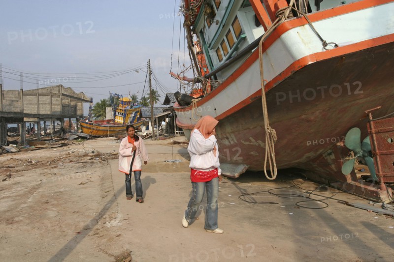 THAILAND, Phang Nga District, Nam Khem, "Tsunami. People walk past boats that have been pushed onto the streets in the village, nothing is left standing in. 2500 people are pressumed dead. 125kms north of Phuket on the 2nd Jan."