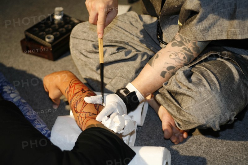 THAILAND, Phuket, Man having tattoo applied to arm.