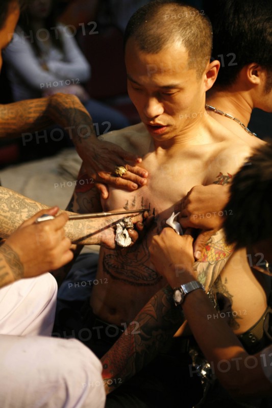 THAILAND, Phuket, Man having tattoo applied to torso.