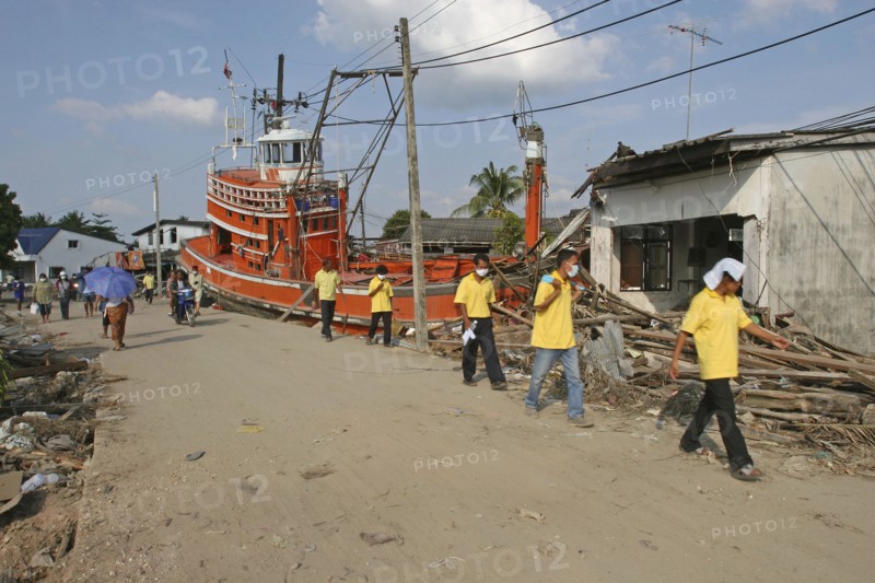 THAILAND, Phang Nga District, Nam Kem, "Tsunami. Volunteers and the locals walk past a fishing boat ploughed into a house. The damage caused by the tsunami, nothing is left standing in the village, about 125kms north of Phuket on the 31st Dec."