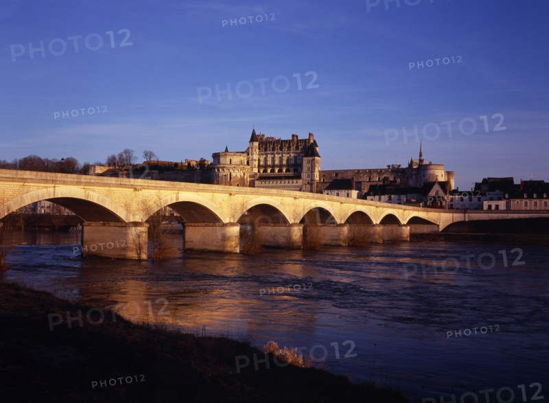 FRANCE, Indre et Loire, Amboise, Chateau at Amboise and bridge seen from the flowing River Loire. Viewed in the evening with golden light.