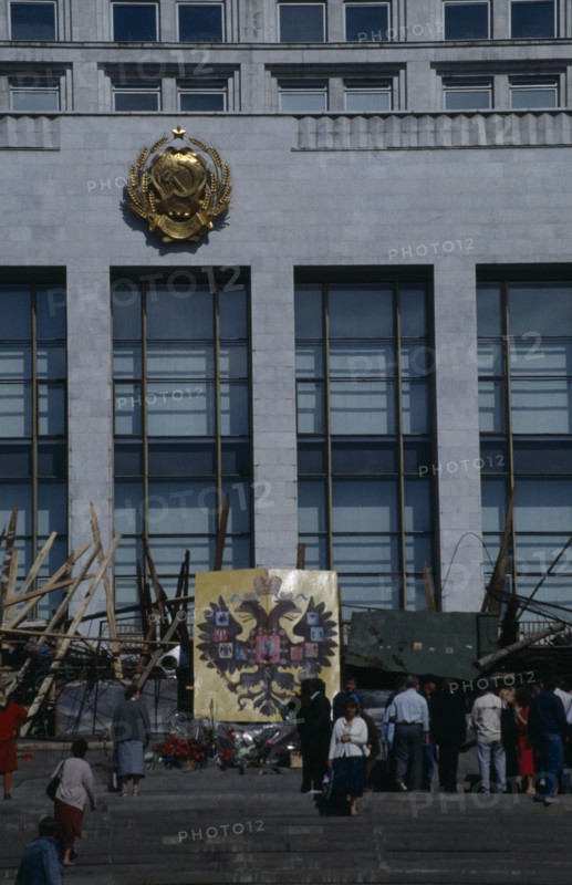 RUSSIA, Moscow, Parliament building with barricades made from pieces of wood and metal after an attempted coup. People standing on the steps next to the Coat of Arms of the Russian Federation emblem which depicts a double headed eagle.