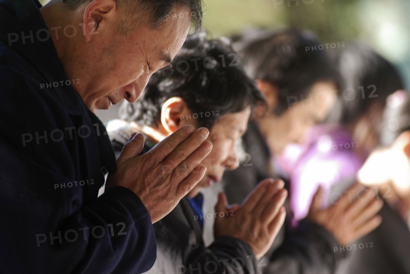 JAPAN, Honshu, Tokyo, "Jingumae - at Meijijingu shrine, line of New Years worshippers praying, in fore man over sixty years old"